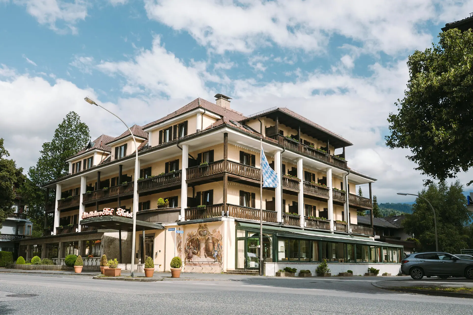 Außenansicht HENRI Hotel Garmisch-Partenkirchen mit Bäumen und einer Straße.
