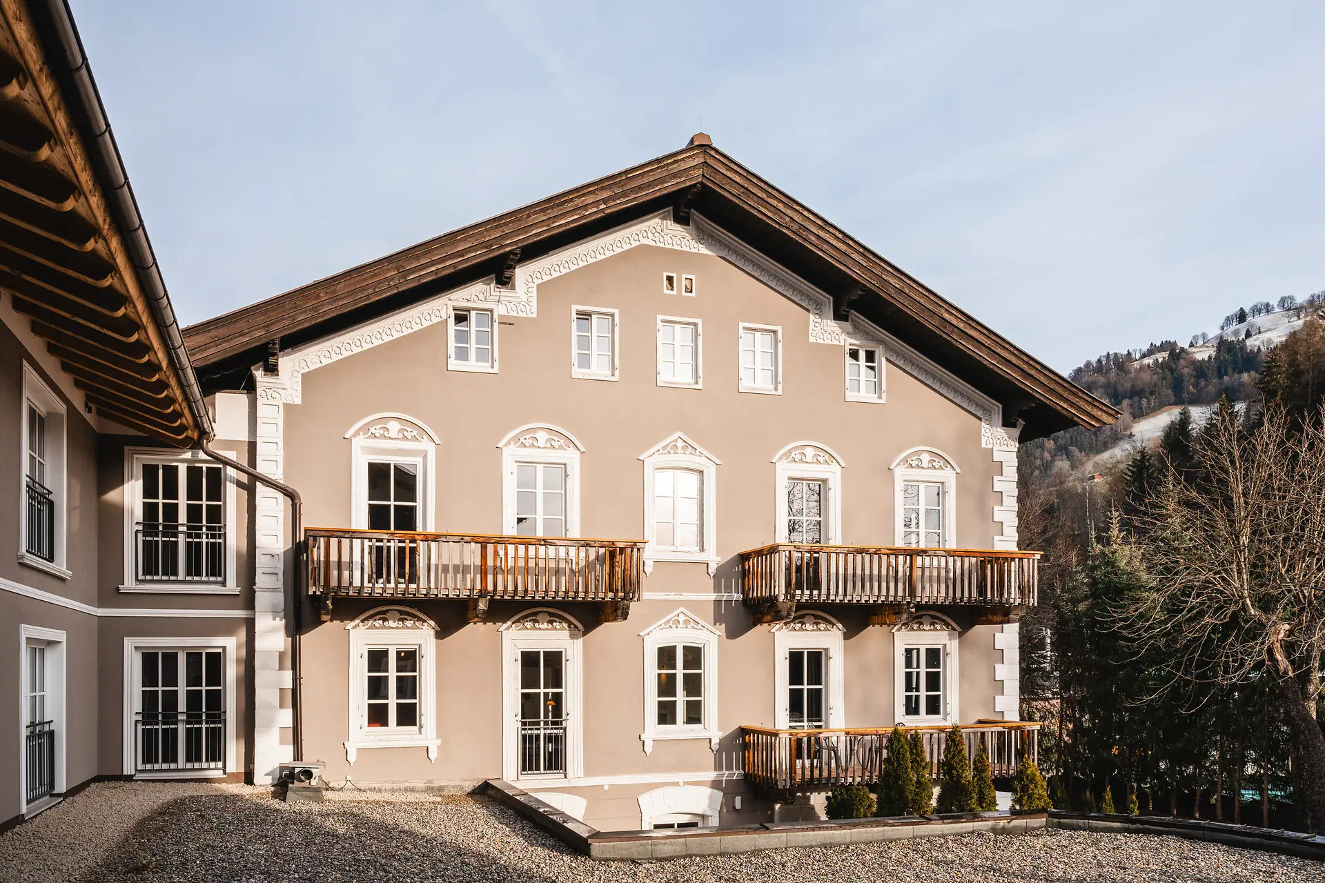 HENRI Kitzbühel – Buitenkant Een gebouw met veel ramen en een oprit.